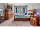 Main bedroom with dresser and nightstand, cozy carpet, and bright windows with stylish blue curtains at 260 Sw Lincoln N Cir, St Petersburg, FL 33703
