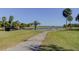 Scenic golf course view with a pond, bridge, palm trees, and a path for walking or golf carts at 2614 Cove Cay Dr # 409, Clearwater, FL 33760
