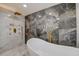 Opulent bathroom featuring marble tiling, a soaking tub, and a luxurious shower setup with gold fixtures at 2679 Haines Bayshore Rd, Clearwater, FL 33760