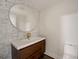Contemporary bathroom with a unique round mirror, marble tile accents, and a wooden vanity at 2679 Haines Bayshore Rd, Clearwater, FL 33760