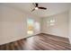 Bright bedroom features wood-look floors, ceiling fan, and a window overlooking the backyard at 2679 Haines Bayshore Rd, Clearwater, FL 33760