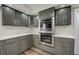 Updated kitchen with gray cabinets, quartz countertops, stainless steel double oven, and tile backsplash at 2679 Haines Bayshore Rd, Clearwater, FL 33760