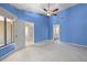Bedroom featuring blue walls, a fan, and access to a bathroom and outdoor balcony at 3066 Landmark Blvd # 1305, Palm Harbor, FL 34684