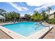 This large community pool features steps and railings, providing ease of access, surrounded by lounge chairs and palm trees at 3066 Landmark Blvd # 1305, Palm Harbor, FL 34684