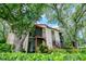 Charming home exterior with a screened porch and second-floor balcony, surrounded by mature trees and greenery at 3455 Countryside Blvd # 31, Clearwater, FL 33761