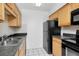 Functional kitchen featuring black appliances, wood cabinets, and a stainless steel double sink at 3455 Countryside Blvd # 31, Clearwater, FL 33761