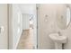 Powder room with pedestal sink, round mirror, and view into adjacent room at 36557 Night Strawberry Ct, Dade City, FL 33525
