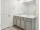 A bathroom features double sinks with light gray cabinets, a mirror, and access to the toilet room at 36557 Night Strawberry Ct, Dade City, FL 33525
