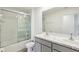 Bathroom featuring a shower with glass doors, double sinks with grey cabinets, and a large mirror at 36557 Night Strawberry Ct, Dade City, FL 33525