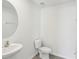 Minimalist powder room features a pedestal sink, round mirror, and modern fixtures at 36557 Night Strawberry Ct, Dade City, FL 33525