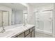 Bathroom features double sinks with gray cabinets and a glass shower with white tiling at 36557 Night Strawberry Ct, Dade City, FL 33525