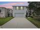 Two-story home featuring a two-car garage, tidy lawn, and charming green shutters at dusk at 36557 Night Strawberry Ct, Dade City, FL 33525