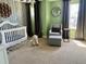 Comfortable Bedroom featuring a crib, gray chair, and patterned wallpaper at 4407 Scarlet Loop, Wesley Chapel, FL 33544