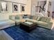 Spacious living room with large sectional, blue rug, dark ottoman, and artful wall decor at 4407 Scarlet Loop, Wesley Chapel, FL 33544