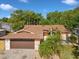 An aerial view of a home with a brown roof near mature trees and a swimming pool at 4519 Swallowtail Dr, New Port Richey, FL 34653