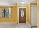 A yellow foyer featuring a decorative front door, tiled flooring, and a side window at 4519 Swallowtail Dr, New Port Richey, FL 34653