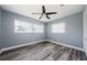 A serene bedroom with hardwood floors, a ceiling fan, and two sunlit windows at 4704 Shale Pl, Tampa, FL 33615