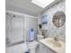 Bright bathroom featuring a tub with sliding doors, blue floral wallpaper, and a round mirror above the vanity at 4900 Brittany S Dr # 805, St Petersburg, FL 33715