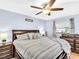 Comfortable bedroom features a ceiling fan, large window, hardwood floor and side tables at 5021 Roanoke Dr, Holiday, FL 34690