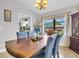 Formal dining room featuring chandelier, wood table with blue upholstered chairs, and backyard views at 5021 Roanoke Dr, Holiday, FL 34690