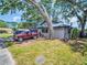 Side exterior of a single-story home with a mature tree and a red truck parked outside at 5021 Roanoke Dr, Holiday, FL 34690