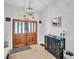 Inviting foyer featuring a wooden door, stylish light fixture, and a modern cabinet at 5021 Roanoke Dr, Holiday, FL 34690