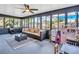 Bright sunroom featuring a ceiling fan, neutral furniture, exercise equipment, and large windows overlooking the yard at 5021 Roanoke Dr, Holiday, FL 34690