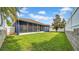 This backyard has a privacy fence, a screened in patio, and lush grass at 650 Arbor Ln, Largo, FL 33770