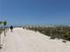 Sandy beach path leading to the ocean with beachgoers and umbrellas in the distance at 6700 Sunset Way # 206, St Pete Beach, FL 33706