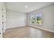Well-lit bedroom featuring light wood flooring and two windows with scenic views at 7236 Sutton Ln, Sarasota, FL 34240
