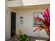 Condo entrance featuring unit number, a decorative sign, and tropical plants, creating a welcoming outdoor foyer at 7701 Starkey Rd # 443, Seminole, FL 33777