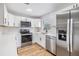 This kitchen features stainless steel appliances, white cabinets, subway tile backsplash and light wood flooring at 8107 N 11Th St, Tampa, FL 33604