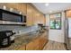 Well-lit kitchen featuring granite countertops, stainless steel appliances, and wood cabinetry at 865 S Gulfview Blvd # 308, Clearwater, FL 33767