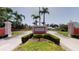 Community entrance with lush greenery, well-maintained lawns, and tall palm trees enhancing curb appeal at 8703 Bardmoor Blvd # 305, Seminole, FL 33777