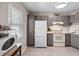 Compact kitchen with white appliances, grey cabinets, and a bright window for natural light at 8703 Bardmoor Blvd # 305, Seminole, FL 33777