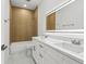 Modern bathroom featuring a double sink vanity, lighted mirror, wood-look tile shower, and white marble floors at 8906 N Otis Ave, Tampa, FL 33604