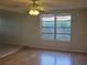 Bright living room featuring hardwood floors, a ceiling fan, and a large window overlooking the backyard at 1408 Oleander Dr, Tarpon Springs, FL 34689