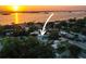 Sunset aerial view of property with a swimming pool, mature trees, and waterfront views with a boat sailing at 1039 Union St, Clearwater, FL 33755