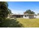 Wide view of the backyard showing the large, grassy area, mature trees, and screened lanai at 1039 Union St, Clearwater, FL 33755