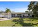 Charming single-story home featuring a well-manicured lawn, palm tree and inviting entryway with stylish Adirondack chairs at 1039 Union St, Clearwater, FL 33755