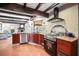 Rustic kitchen featuring wood beams, terracotta floors, stainless steel appliances and decorative brick surrounding the stove at 1039 Union St, Clearwater, FL 33755