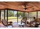 Relaxing screened lanai with a wood ceiling, fan, and wicker furniture overlooking the lush backyard and water fountain at 1039 Union St, Clearwater, FL 33755