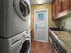 Functional laundry area with a stacked washer/dryer, a sink, granite countertops, and backyard access door at 1039 Union St, Clearwater, FL 33755