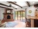 Living room showcasing a brick fireplace, beamed ceiling, and access to an outdoor screened-in lanai with a fountain at 1039 Union St, Clearwater, FL 33755