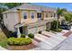 Two-story tan townhome featuring an attached garage, lush landscaping, and a driveway for convenient parking at 1051 Andrew Aviles Cir, Tampa, FL 33619