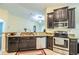 Kitchen boasts stainless steel appliances, dark wood cabinets, and granite countertops at 16616 Magnolia Reserve Pl, Wimauma, FL 33598