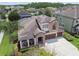 Aerial view of a two-story home showcases a well-maintained yard, lush landscaping, and a three-car garage at 1796 Tonka Ter, Wesley Chapel, FL 33543