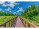 Scenic wooden boardwalk winds through a lush green landscape under a bright blue sky with scattered clouds at 1796 Tonka Ter, Wesley Chapel, FL 33543