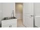 Modern laundry room with stainless steel sink, white cabinetry, and access door to additional space at 1796 Tonka Ter, Wesley Chapel, FL 33543