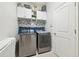 Well-lit laundry room features gray mosaic backsplash, newer washer and dryer, and convenient upper cabinet storage at 1796 Tonka Ter, Wesley Chapel, FL 33543